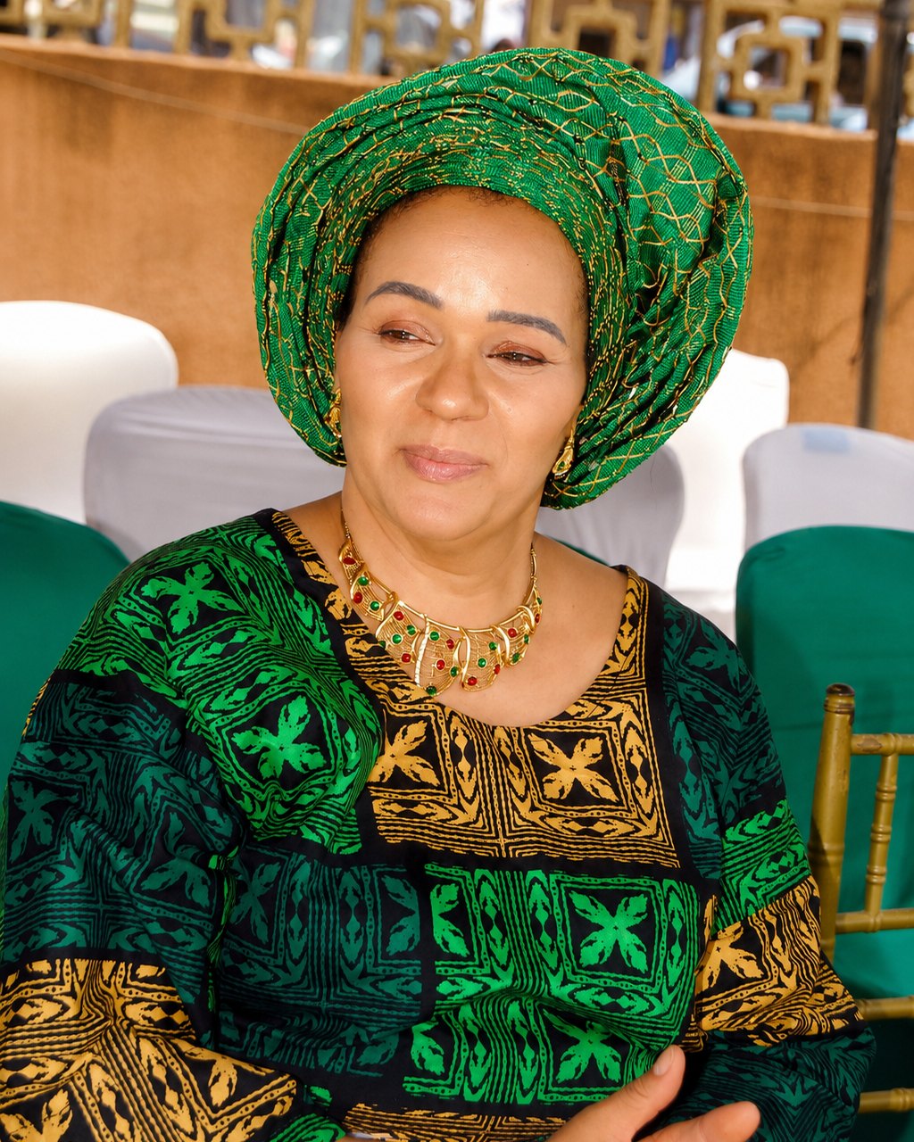 MIO seated in green traditional attire with a matching gele