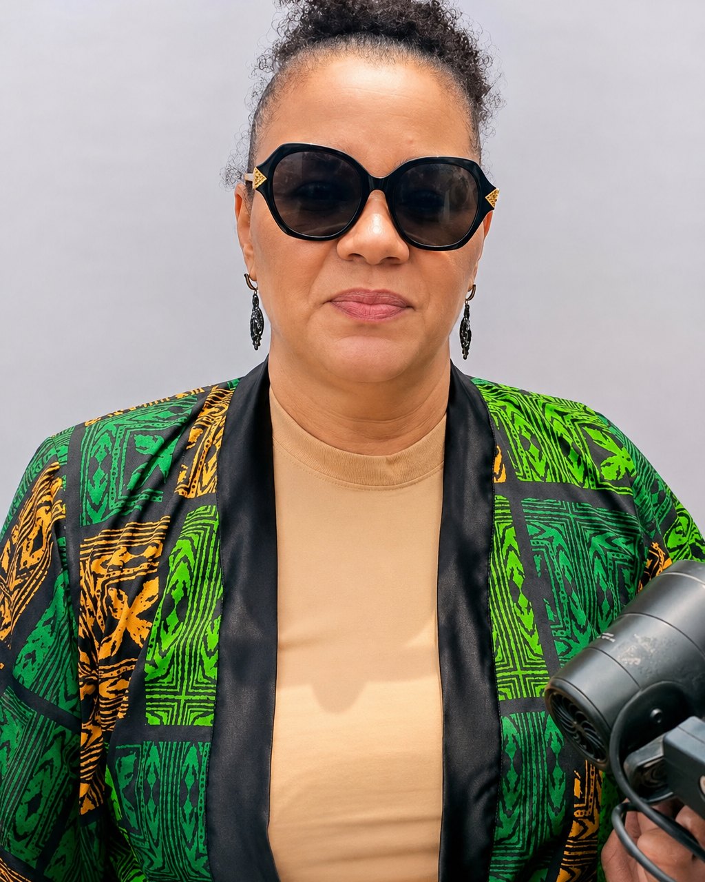 MIO wearing sunglasses and a green patterned jacket